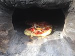 HURRA !!! Die erste Pizza (ok, das hier war schon die zweite ...) ist fertig!!<br />Deutlich schneller, als erwartet!<br />Vor lauter Übermut und Eifer ist die Pizza noch nicht ganz fertig getillert (d.h. der Teig ist nicht ganz gebacken), schmeckt aber mit mineralischer Ascheeinlage trotzdem hervorragend.<br />Es stellt sich heraus, dass die vorne liegenden Pizzen (da war das Feuer) deutlich fertiger sind, als die hinten im Brennraum liegenden.<br />Dennoch - diese ersten Pizzen sind auf jeden Fall als Erfolg zu verbuchen.