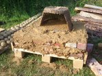 Die Steinlagen sind fertig. Oben auf wurde eine ca. 3 cm dicke Granitplatte als Backraumboden in Lehm gelegt. Darauf ein alter Holzkorb von Kai. Der soll dem Lehm die Form geben.